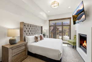Plush carpeted room featuring an integrated fireplace, large window with outdoor scenery, recessed lighting, and a contemporary ceiling fixture