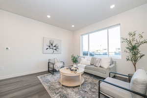 Living room with dark wood-type flooring and recessed lighting