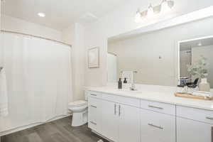 Bathroom with a shower with shower curtain, vanity, dark wood-style flooring, and recessed lighting