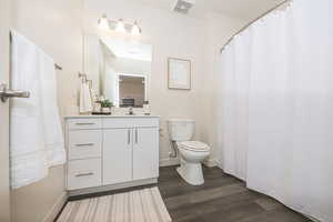 Full bath with a shower with curtain, vanity, and dark wood finished floors
