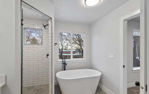 Primary bathroom featuring soft close cabinets, a glass shower door, and a stand alone tub