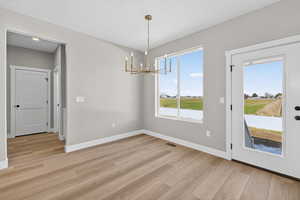 Unfurnished dining area featuring a chandelier and light wood-type flooring