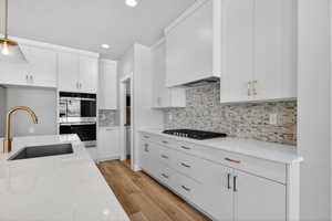 Kitchen with white cabinets, pendant lighting, stainless steel appliances, light stone counters, and recessed lighting