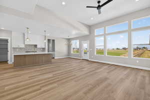 Unfurnished living room featuring a chandelier, a ceiling fan, light wood-type flooring, and recessed lighting