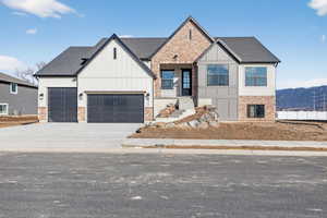 View of front of house with driveway, board and batten siding, brick siding, and a shingled roof