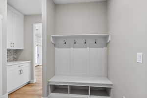 Mudroom with light wood-type flooring and baseboards