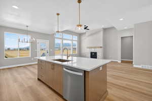 Kitchen featuring stainless steel dishwasher, a glass covered fireplace, recessed lighting, open floor plan, and pendant lighting