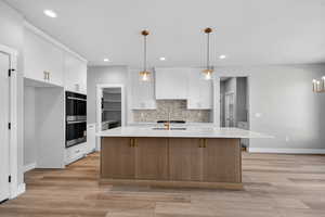 Kitchen featuring pendant lighting, brown cabinets, white cabinetry, and recessed lighting