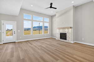 Unfurnished living room featuring light wood-style flooring, a fireplace, a ceiling fan, recessed lighting, and a mountain view