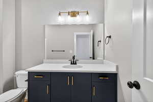 Half bathroom featuring vanity and toilet