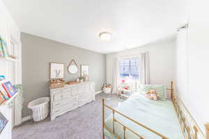 Bedroom featuring light colored carpet and a textured ceiling