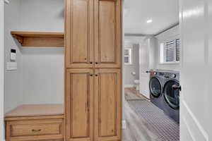 Laundry room featuring light wood finished floors, washing machine and dryer, cabinet space, and recessed lighting