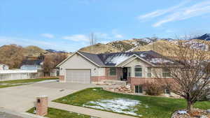 Ranch-style house featuring concrete driveway, brick siding, a mountain view, stucco siding, and a garage