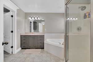 Bathroom with a bath, vanity, a shower stall, and light tile patterned floors