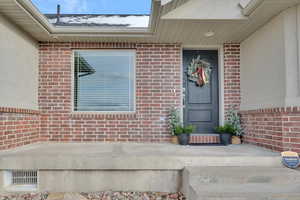 View of exterior entry with brick siding and stucco siding