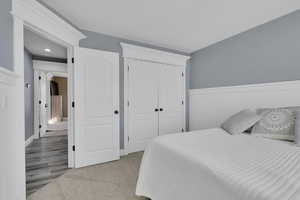 Bedroom with a closet, wainscoting, and light colored carpet