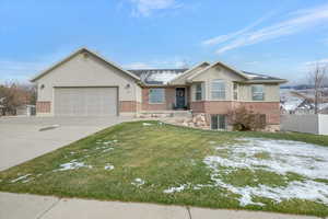 Single story home with driveway, stucco siding, a garage, and brick siding