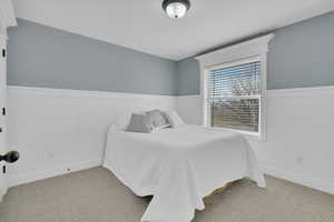 Bedroom featuring a wainscoted wall and light colored carpet