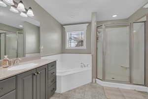 Full bathroom featuring vanity, a shower stall, a bath, recessed lighting, and light tile patterned floors