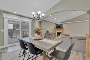 Dining space with a fireplace, lofted ceiling, recessed lighting, light wood-style floors, and a chandelier