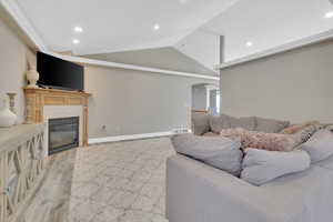 Living area with recessed lighting, lofted ceiling, arched walkways, a fireplace, and light wood-style floors