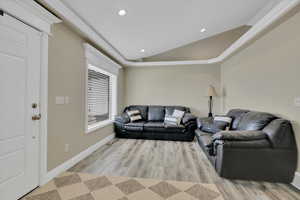 Living room with lofted ceiling, light wood-style floors, and recessed lighting