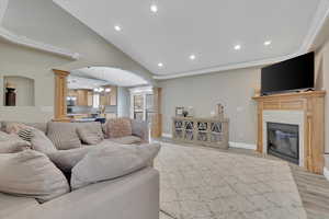 Living area with arched walkways, ornate columns, a chandelier, light wood-style floors, and recessed lighting