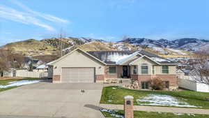 Ranch-style house featuring a mountain view, stucco siding, concrete driveway, and brick siding