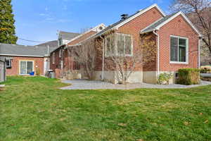 Rear view of property with brick siding and a lawn
