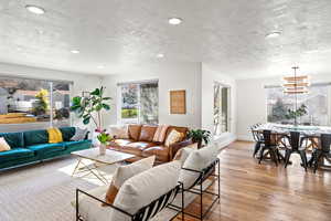 Living area with light wood-style floors, a textured ceiling, and hanging lights