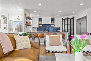 Kitchen with white cabinets, wood finished floors, open shelves, open floor plan, and recessed lighting