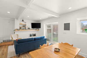 Dining area featuring beam ceiling, light wood-style flooring, recessed lighting, and a glass covered fireplace