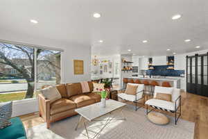 Living room with a barn door, light wood finished floors, and recessed lighting