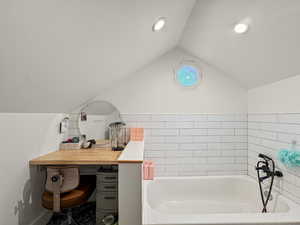 Full bathroom with vaulted ceiling, a garden tub, and vanity