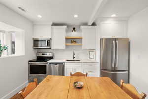 Kitchen with open shelves, stainless steel appliances, white cabinetry, recessed lighting, and backsplash