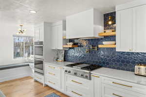 Kitchen featuring open shelves, light stone countertops, white cabinets, stainless steel appliances, and a textured ceiling