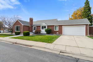 Ranch-style house with roof with shingles, a front yard, driveway, an attached garage, and brick siding