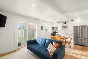 Living room with recessed lighting, beamed ceiling, and light wood-style flooring