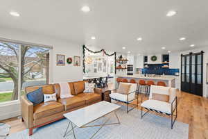 Living area featuring a barn door, light wood finished floors, and recessed lighting