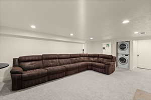 Living area featuring light carpet, estacked washer and dryer, and recessed lighting