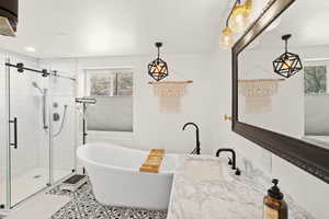 Bathroom with a freestanding bath, vanity, a stall shower, and tile patterned flooring