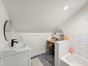 Bathroom featuring vanity, a garden tub, and vaulted ceiling