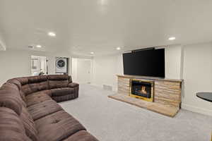 Carpeted living area featuring a fireplace, stacked washer and clothes dryer, and recessed lighting