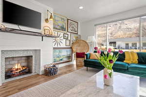 Living room with wood finished floors, a tile fireplace, and recessed lighting