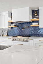 Kitchen with open shelves, light stone countertops, white cabinetry, extractor fan, and a textured ceiling