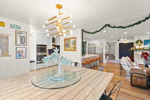 Dining space featuring stairs, light wood-style floors, a chandelier, and recessed lighting