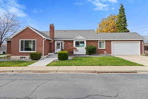 Single story home with roof with shingles, a front yard, brick siding, driveway, and a chimney