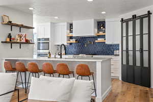 Kitchen featuring open shelves, a kitchen breakfast bar, a peninsula, white cabinetry, and light wood-style floors