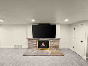 Unfurnished living room with a fireplace, carpet floors, and a textured ceiling