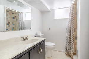 Bathroom featuring light flooring, a shower with shower curtain, a textured ceiling, vanity, and plenty of natural light